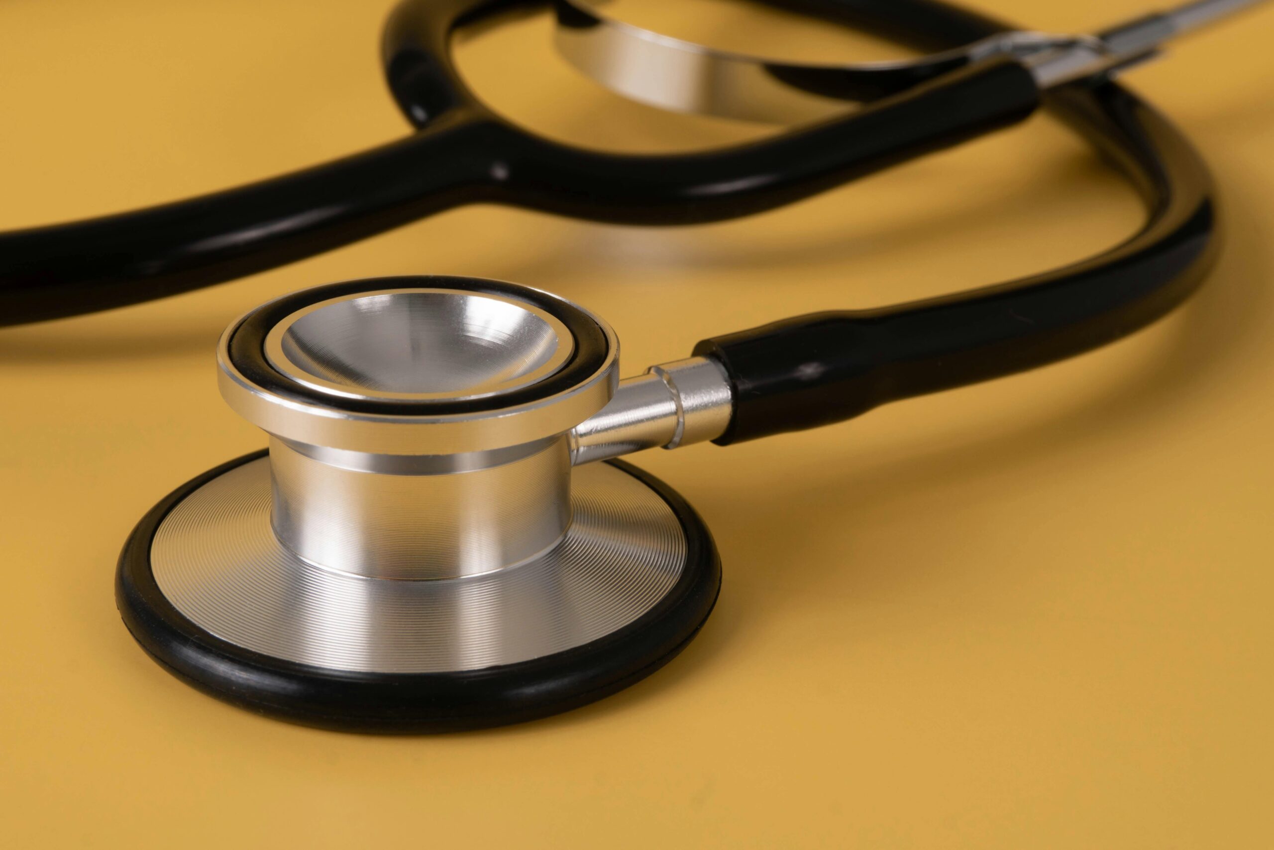 Detailed image of a stethoscope on a vibrant yellow surface.